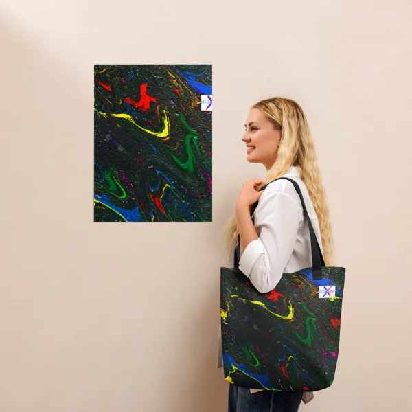 A woman holds a tote bag with bright swirls of red, blue, and yellow mix with green representing the main characters on a glittering charcoal background to invoke the feel of space and black handles over her left shoulder.