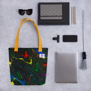 Tote bag with bright swirls of red, blue, and yellow mix with green representing the main characters on a glittering charcoal background to invoke the feel of space and yellow handles surrounded by accessories like sunglasses and a laptop demonstrating what can go into the bag.